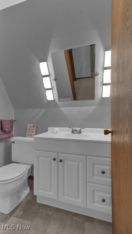 bathroom featuring toilet, vanity, and vaulted ceiling