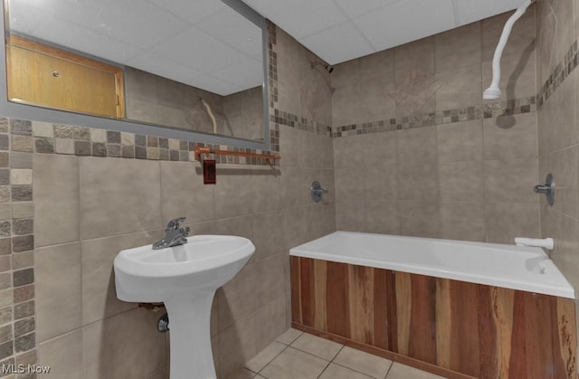 bathroom with tile walls, a paneled ceiling, and tile patterned floors