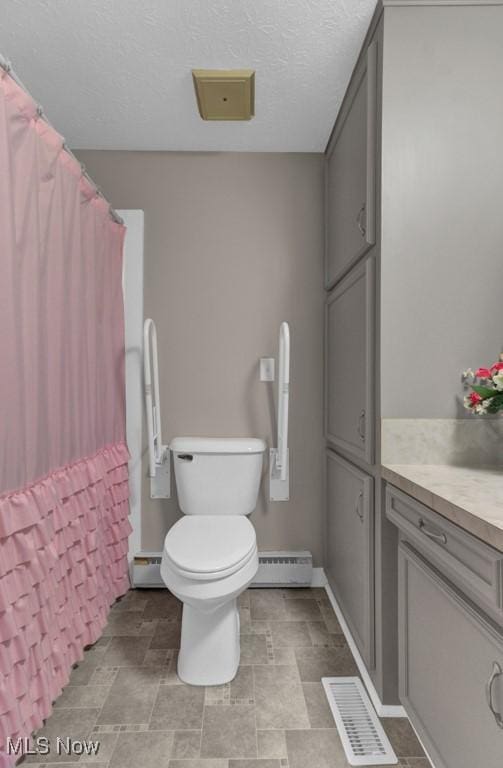 bathroom featuring a textured ceiling, baseboard heating, vanity, and toilet