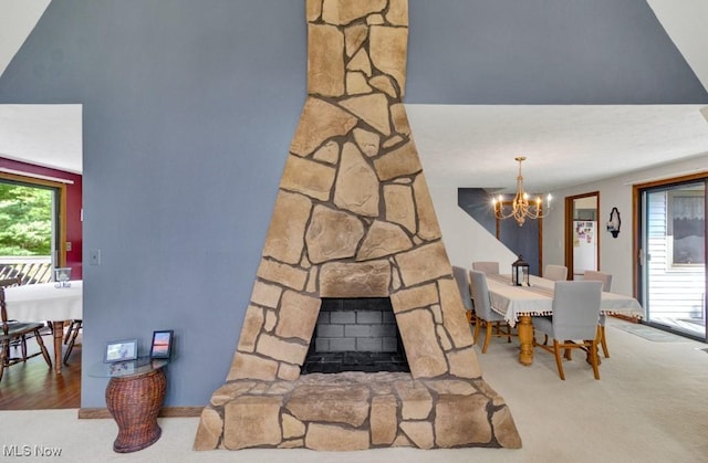 interior space with carpet flooring, a notable chandelier, and a stone fireplace