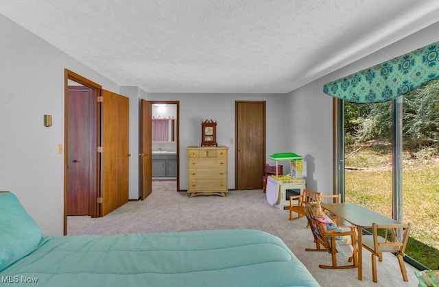 bedroom with a textured ceiling, light carpet, and connected bathroom