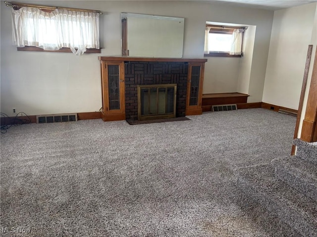 unfurnished living room featuring a brick fireplace and carpet floors