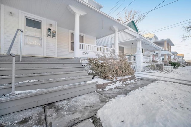 snow covered property entrance with covered porch