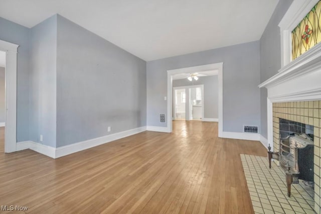 unfurnished living room featuring a fireplace, ceiling fan, and light hardwood / wood-style flooring