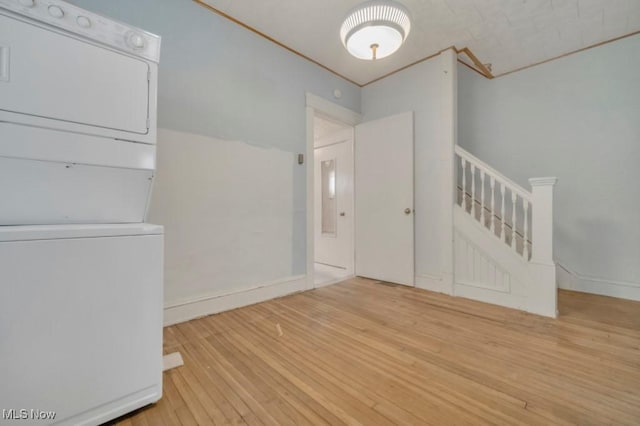 interior space featuring stacked washing maching and dryer, light wood-type flooring, and crown molding