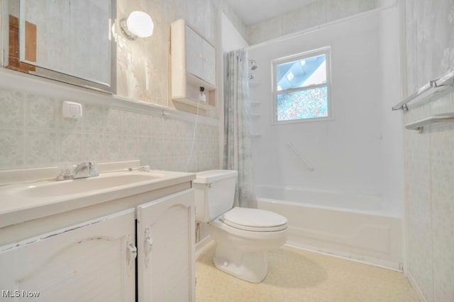 full bathroom featuring shower / bathtub combination with curtain, tile walls, vanity, and toilet