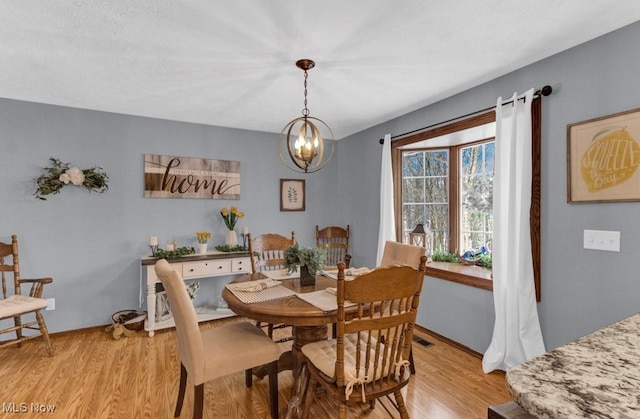 dining area featuring an inviting chandelier and light hardwood / wood-style flooring