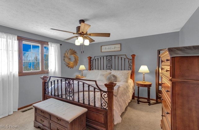 bedroom with ceiling fan, light colored carpet, and a textured ceiling