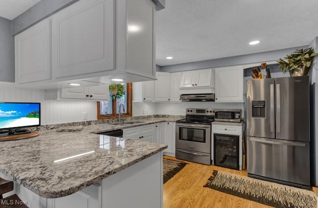 kitchen with sink, stainless steel appliances, kitchen peninsula, and white cabinets