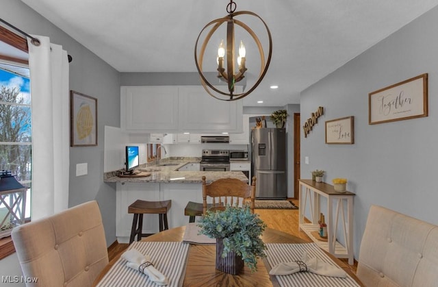 dining area featuring an inviting chandelier, sink, and light hardwood / wood-style flooring