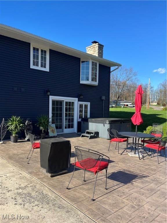 rear view of property featuring a hot tub and a patio area