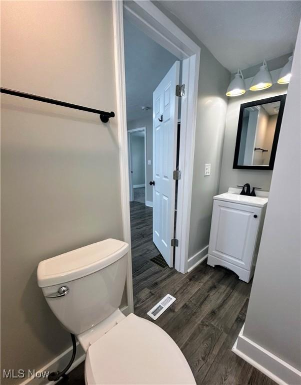 bathroom with toilet, wood-type flooring, and vanity