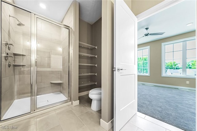 bathroom with toilet, a shower with shower door, ceiling fan, and tile patterned floors