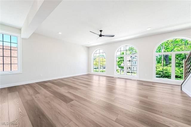 unfurnished room with beam ceiling, ceiling fan, and light hardwood / wood-style flooring