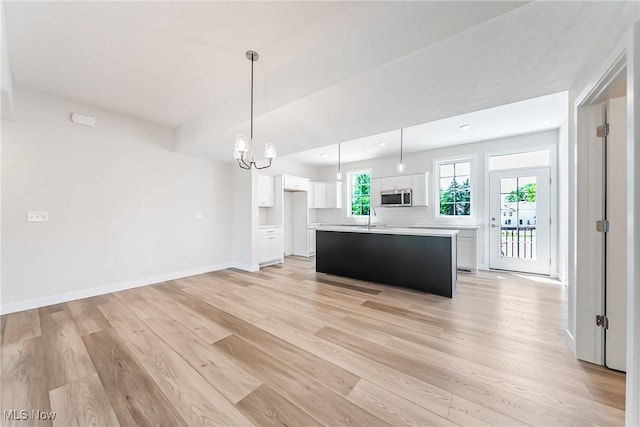 kitchen with white cabinets, an inviting chandelier, light hardwood / wood-style floors, hanging light fixtures, and a kitchen island