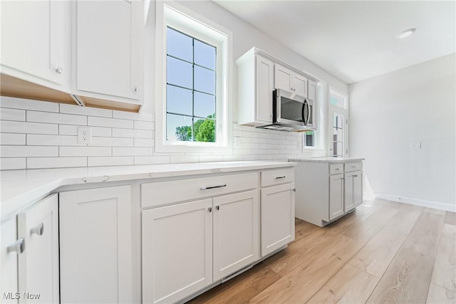 kitchen featuring light hardwood / wood-style floors, decorative backsplash, and white cabinetry