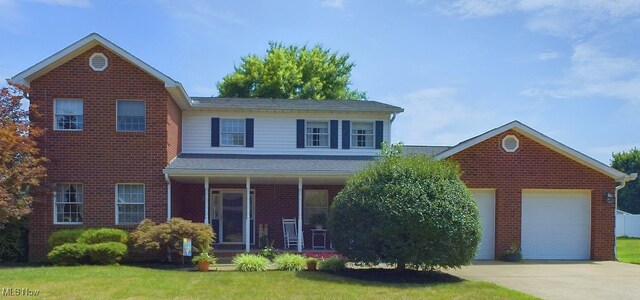 front of property featuring covered porch, a front lawn, and a garage