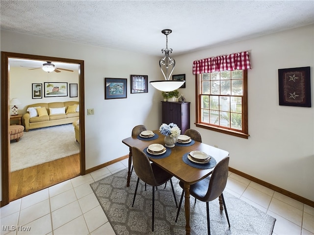 tiled dining space with a textured ceiling and ceiling fan