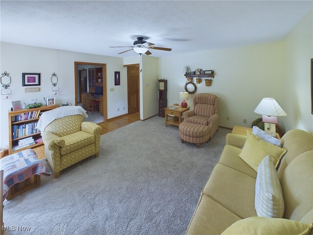 living room featuring carpet flooring, a textured ceiling, and ceiling fan