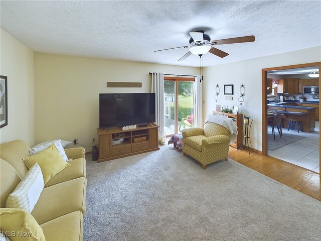 living room with a textured ceiling, hardwood / wood-style floors, and ceiling fan