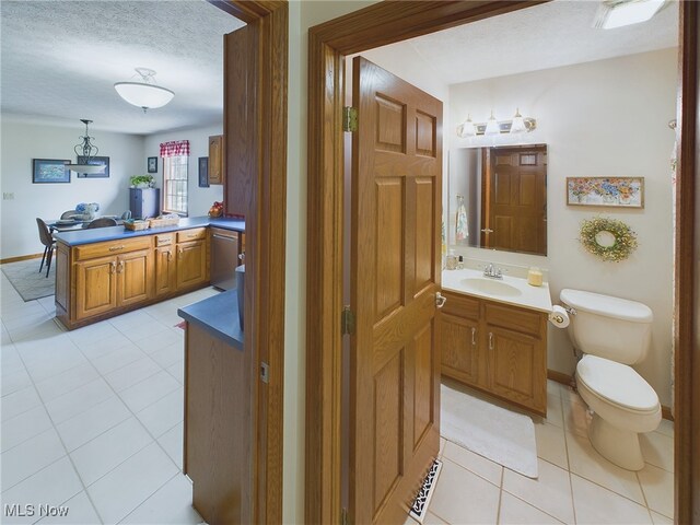 bathroom featuring toilet, a textured ceiling, tile patterned floors, and vanity