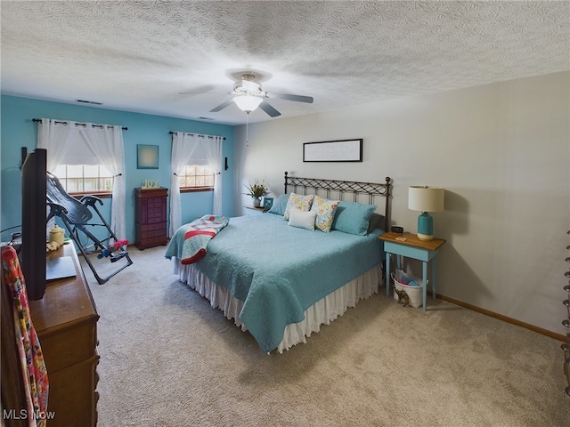 bedroom featuring a textured ceiling, ceiling fan, and light colored carpet