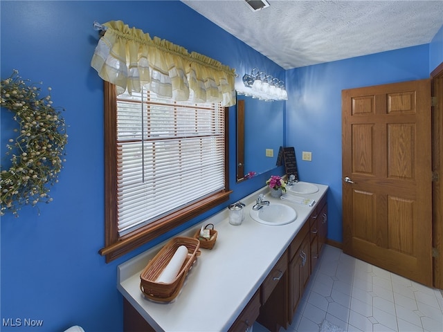 bathroom with a textured ceiling, tile patterned flooring, and vanity