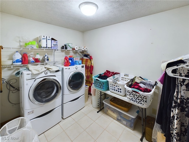 laundry area with a textured ceiling, light tile patterned floors, and washer and clothes dryer