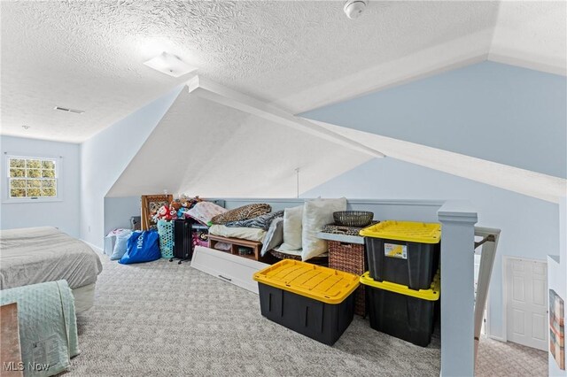 bedroom featuring a textured ceiling, carpet floors, and vaulted ceiling