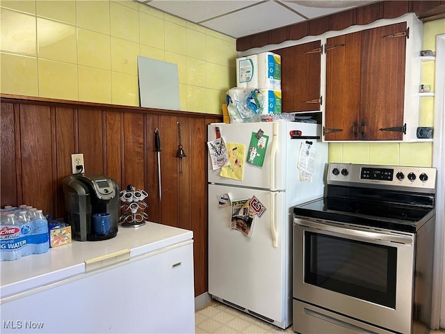 kitchen featuring white fridge, fridge, and stainless steel range with electric cooktop