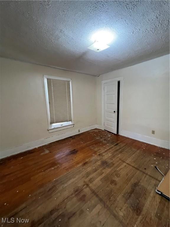 empty room with dark wood-type flooring and a textured ceiling