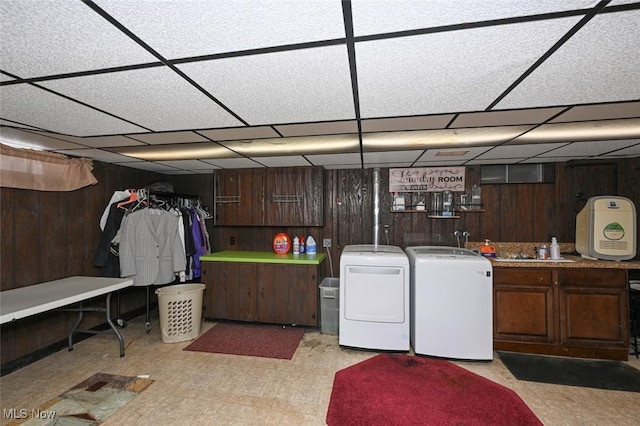 laundry area featuring sink, independent washer and dryer, wooden walls, and cabinets