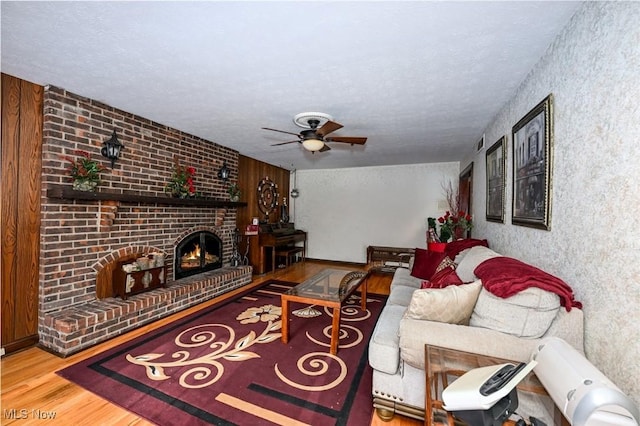 living room featuring a textured ceiling, ceiling fan, a fireplace, and hardwood / wood-style floors