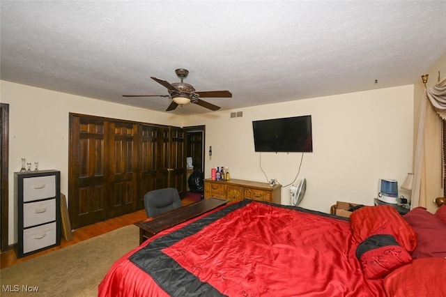 bedroom with a textured ceiling, ceiling fan, a closet, and hardwood / wood-style flooring