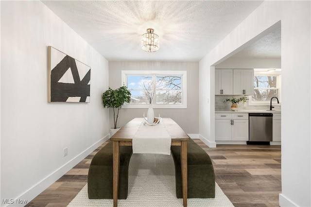 dining room with sink, a textured ceiling, an inviting chandelier, and hardwood / wood-style flooring