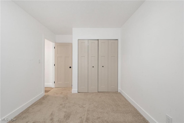 unfurnished bedroom with a closet and light carpet