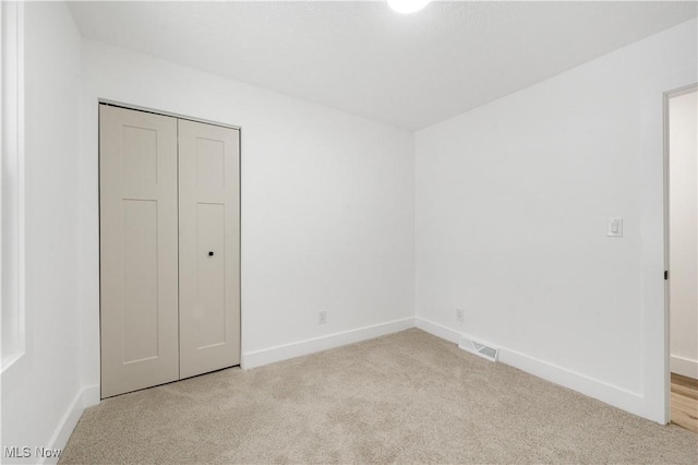 unfurnished bedroom featuring a closet and light carpet