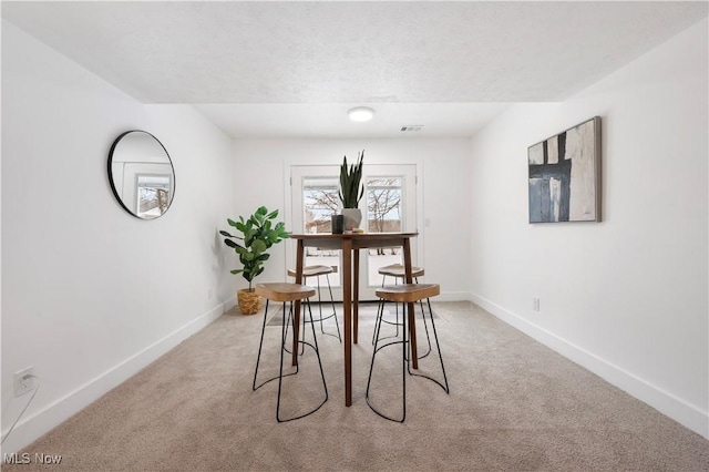 carpeted dining room featuring a textured ceiling