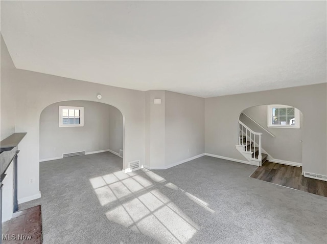 unfurnished living room with dark colored carpet and a healthy amount of sunlight