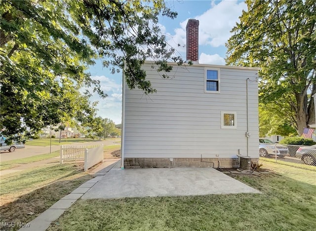 view of side of home with cooling unit, a yard, and a patio