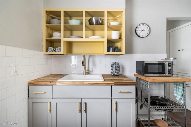 kitchen featuring sink, butcher block countertops, backsplash, and gray cabinets