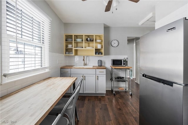 kitchen with sink, white cabinetry, butcher block countertops, dark hardwood / wood-style flooring, and appliances with stainless steel finishes