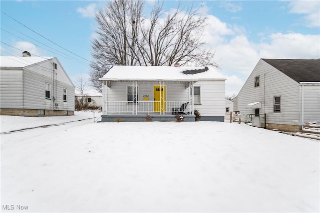 snow covered house featuring a porch