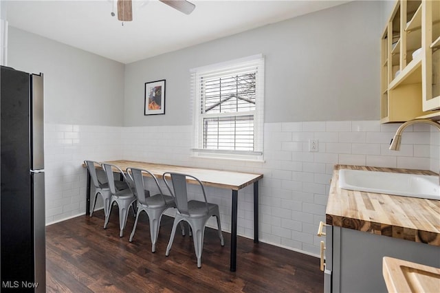 dining space with tile walls, dark hardwood / wood-style floors, and sink