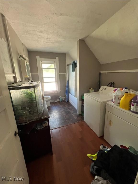 laundry area featuring a textured ceiling, dark wood-type flooring, and washing machine and clothes dryer