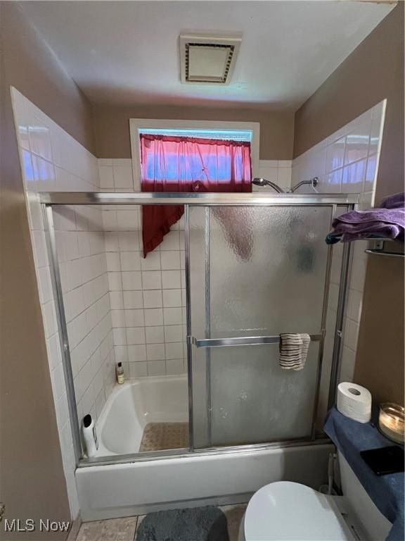 bathroom featuring shower / bath combination with glass door, toilet, and tile patterned floors