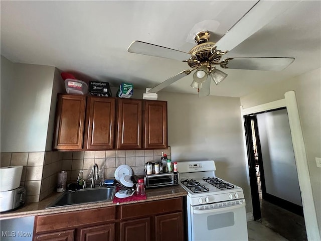 kitchen featuring ceiling fan, white range with gas cooktop, decorative backsplash, and sink