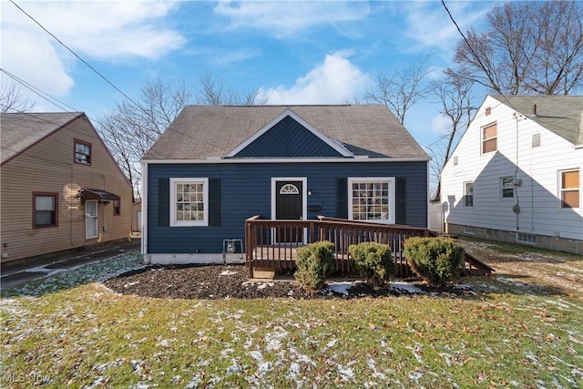 bungalow with a front lawn and a wooden deck