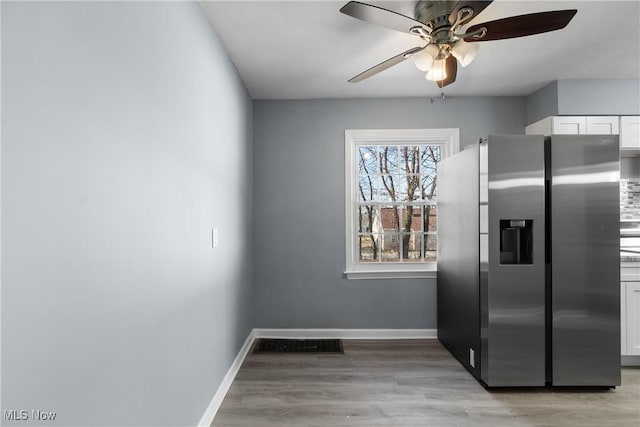 kitchen with ceiling fan, white cabinetry, light wood-type flooring, and stainless steel refrigerator with ice dispenser