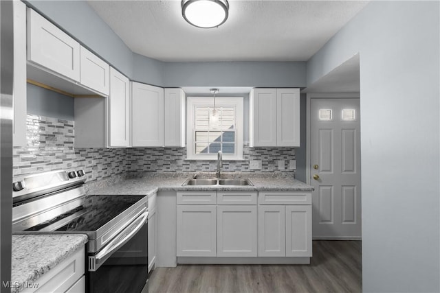 kitchen featuring sink, white cabinets, backsplash, stainless steel range with electric stovetop, and pendant lighting